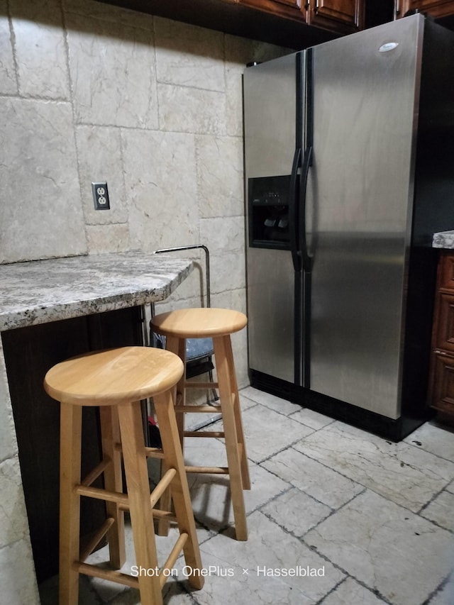 kitchen featuring backsplash, light stone counters, and stainless steel appliances