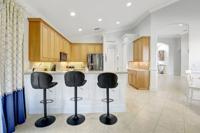 kitchen featuring lofted ceiling, kitchen peninsula, crown molding, appliances with stainless steel finishes, and light stone counters