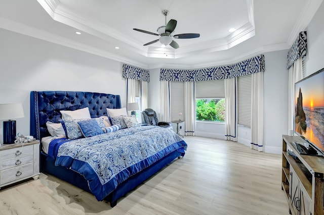 bedroom with ceiling fan, a raised ceiling, ornamental molding, and light hardwood / wood-style flooring