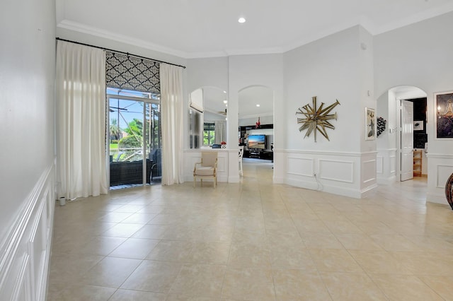 foyer featuring crown molding, a towering ceiling, and light tile patterned floors