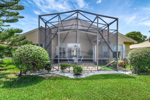 rear view of property with a patio, a lawn, and glass enclosure