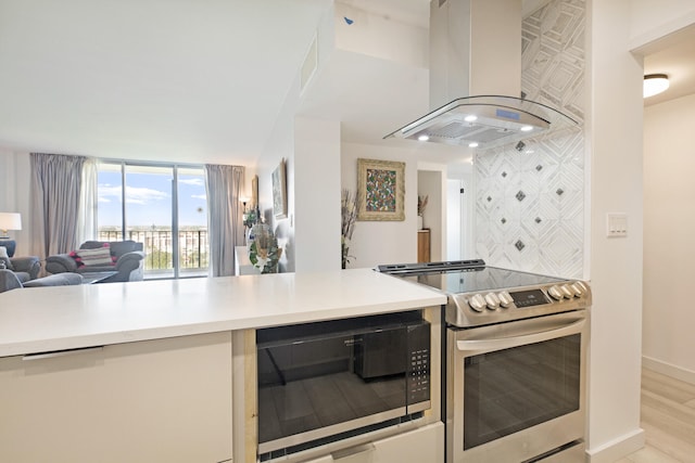 kitchen with appliances with stainless steel finishes, wall chimney range hood, and light wood-type flooring