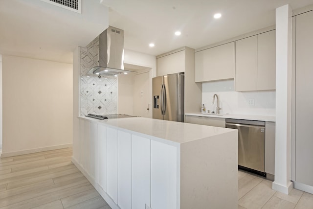 kitchen with island exhaust hood, white cabinetry, stainless steel appliances, and light hardwood / wood-style floors