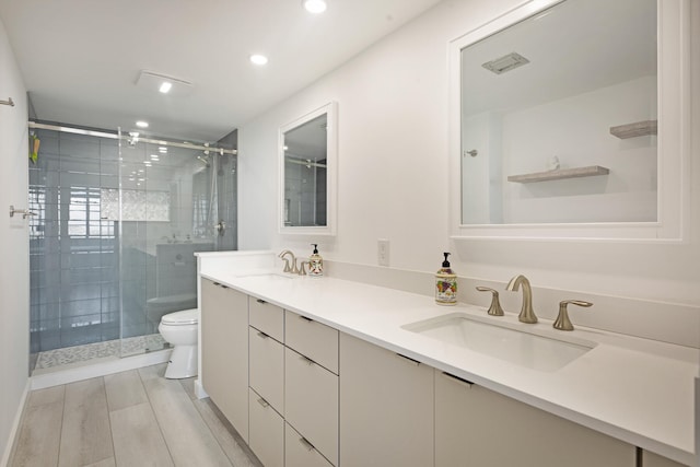 bathroom with toilet, vanity, wood-type flooring, and a shower with door