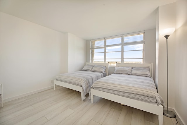 bedroom with light wood-type flooring and baseboards