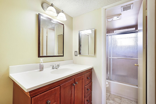 full bathroom featuring vanity, a textured ceiling, shower / bath combination with glass door, and toilet