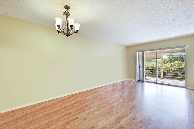 unfurnished room with light hardwood / wood-style floors, an inviting chandelier, and a textured ceiling