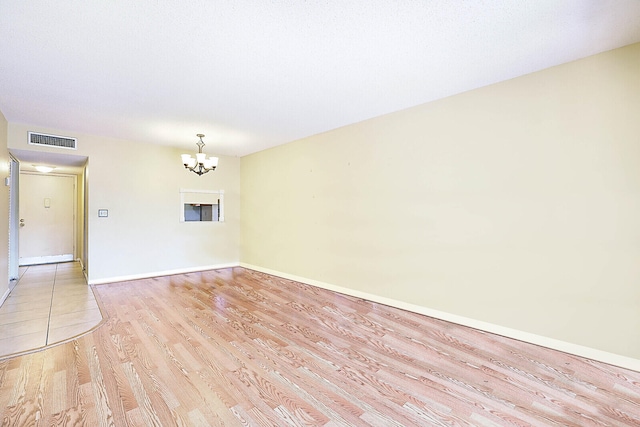 unfurnished room featuring a chandelier and light hardwood / wood-style floors