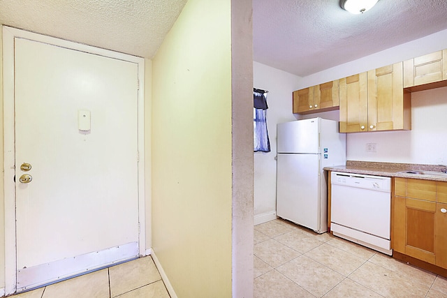 kitchen with sink, a textured ceiling, white appliances, and light tile patterned floors