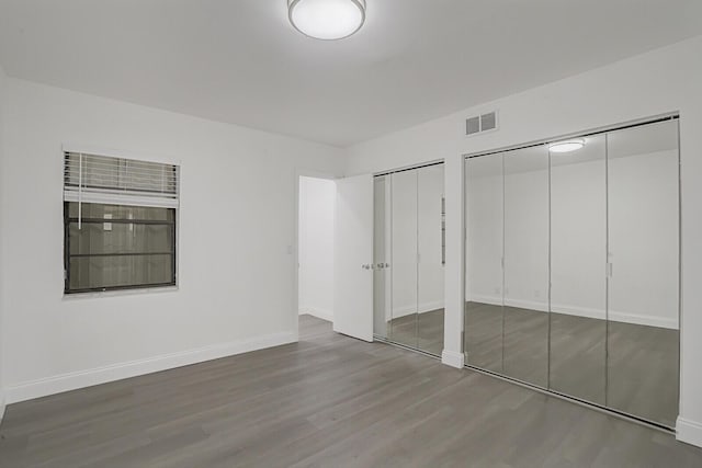 unfurnished bedroom with wood-type flooring and two closets