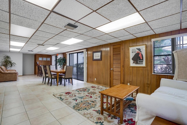 tiled living room with a paneled ceiling and wood walls