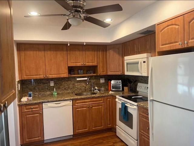 kitchen featuring dark hardwood / wood-style floors, dark stone counters, sink, white appliances, and tasteful backsplash