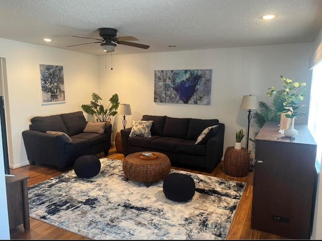 living room with a textured ceiling, wood-type flooring, and ceiling fan