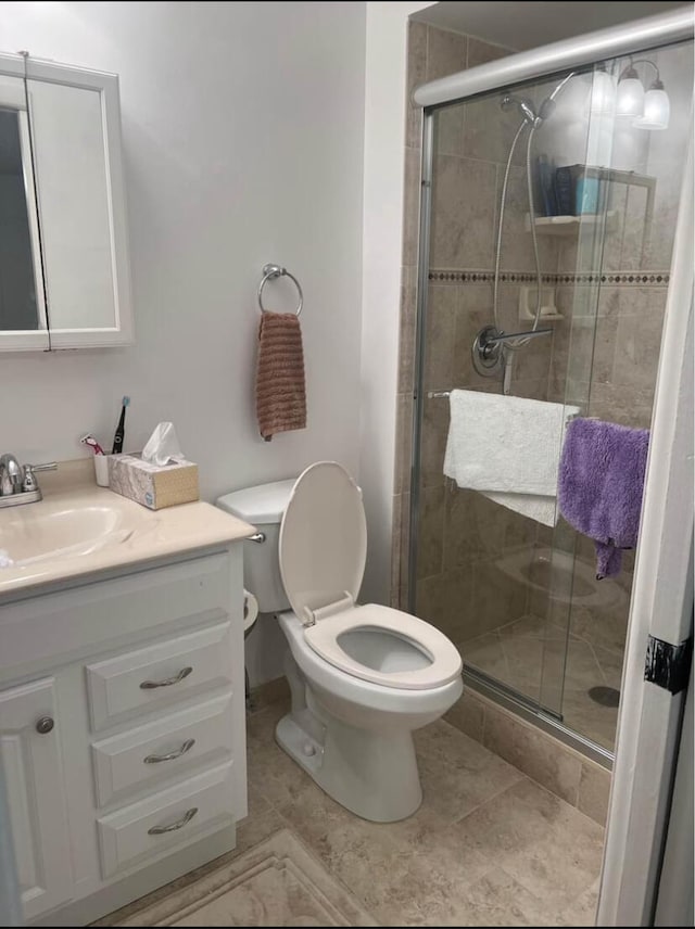 bathroom featuring vanity, toilet, and a shower with door