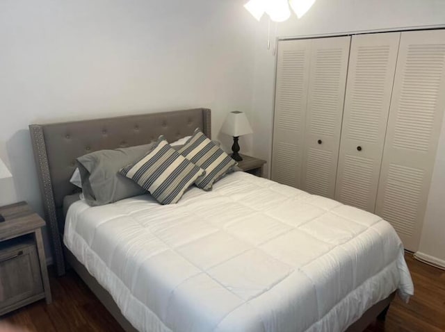 bedroom with dark wood-type flooring and a closet