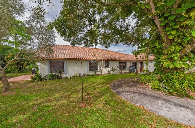 view of front of house with central AC and a front yard