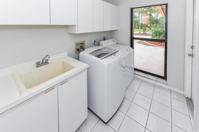 laundry area with sink, light tile patterned flooring, washing machine and dryer, and cabinets