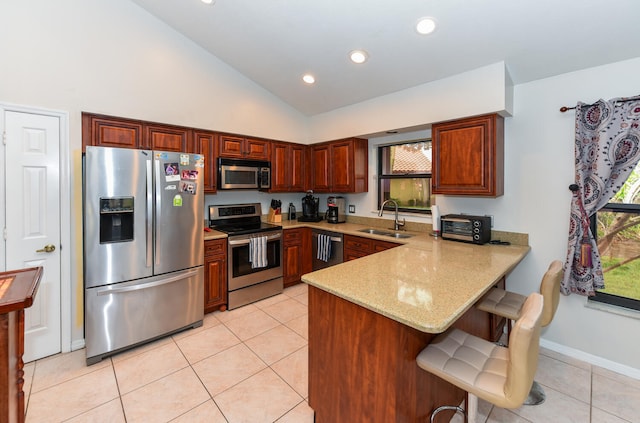 kitchen with kitchen peninsula, light stone counters, appliances with stainless steel finishes, a kitchen breakfast bar, and sink