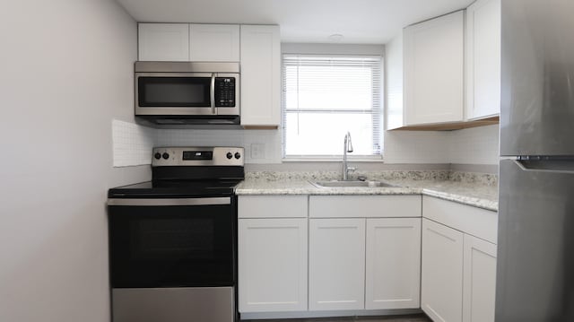 kitchen featuring sink, white cabinets, decorative backsplash, and stainless steel appliances