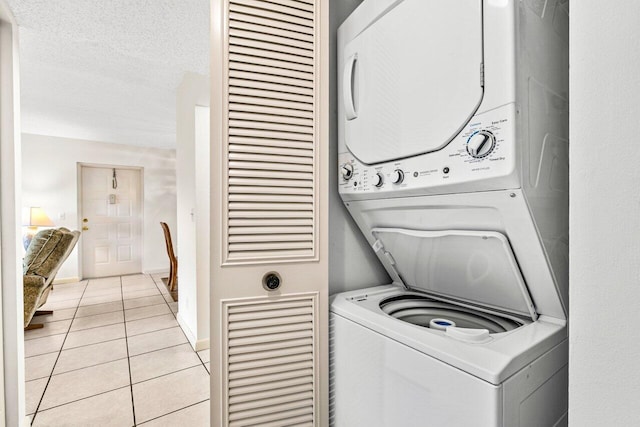 washroom with stacked washer / dryer, a textured ceiling, and light tile patterned floors