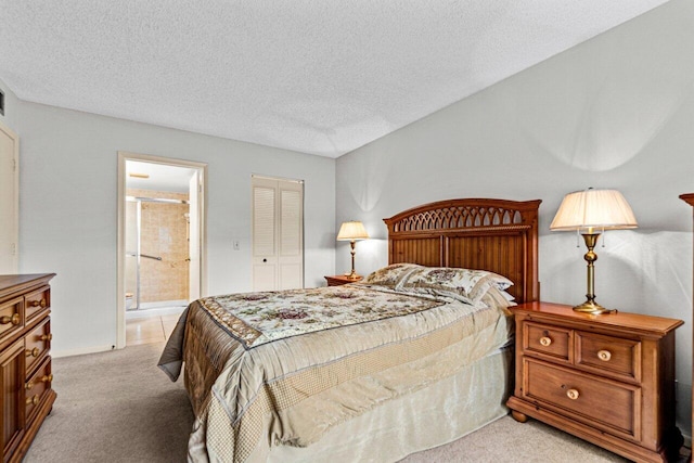 carpeted bedroom with a closet, a textured ceiling, and ensuite bath