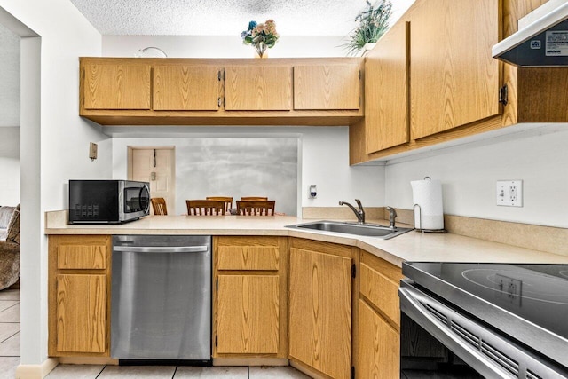 kitchen featuring sink, stainless steel appliances, a textured ceiling, and light tile patterned floors