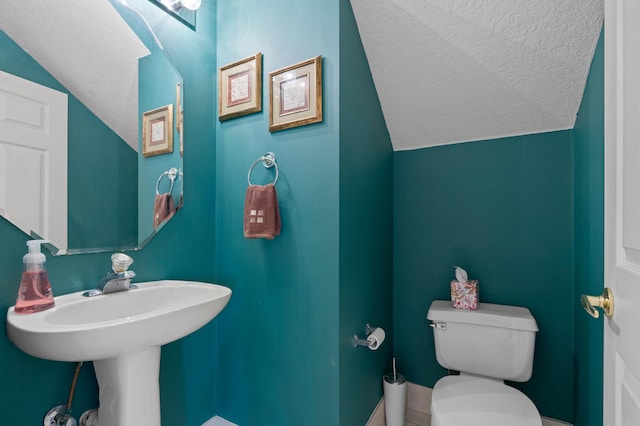 bathroom with lofted ceiling, a textured ceiling, and toilet