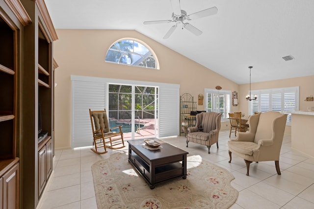 tiled living room featuring high vaulted ceiling and ceiling fan with notable chandelier