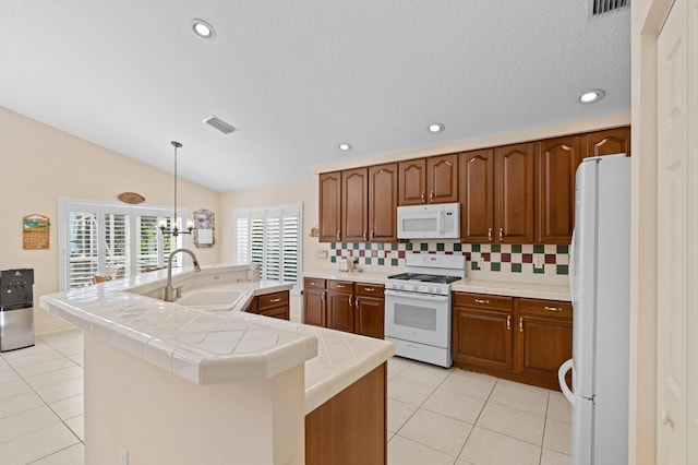 kitchen featuring white appliances, vaulted ceiling, sink, and a kitchen island with sink