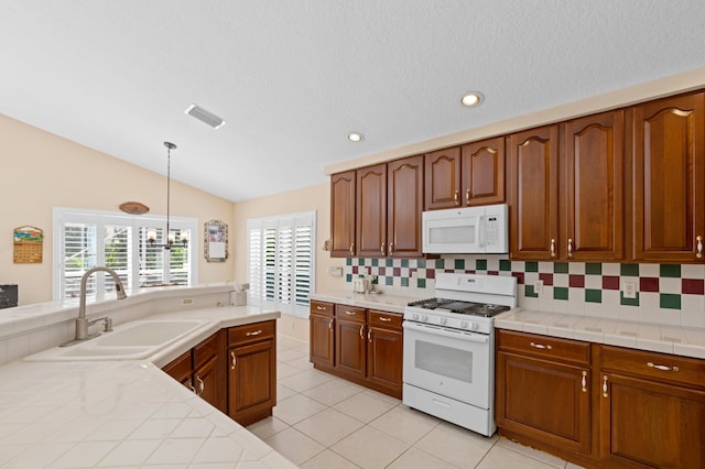 kitchen featuring lofted ceiling, pendant lighting, a notable chandelier, sink, and white appliances