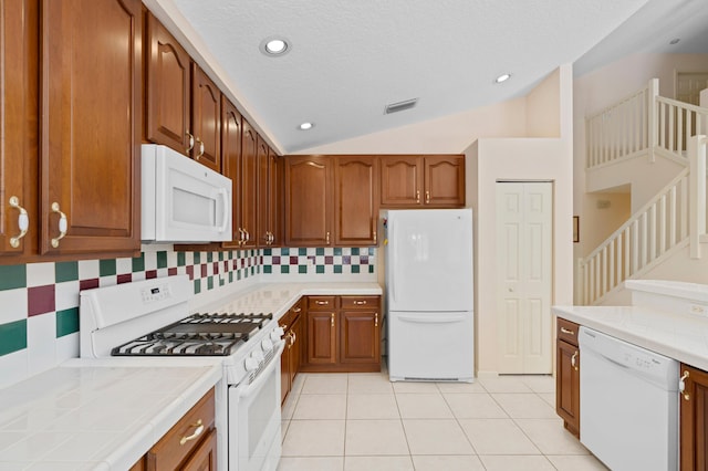 kitchen featuring backsplash, light tile patterned floors, a textured ceiling, vaulted ceiling, and white appliances