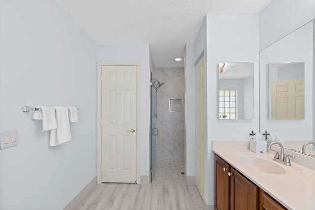 bathroom featuring vanity, hardwood / wood-style floors, a textured ceiling, and walk in shower