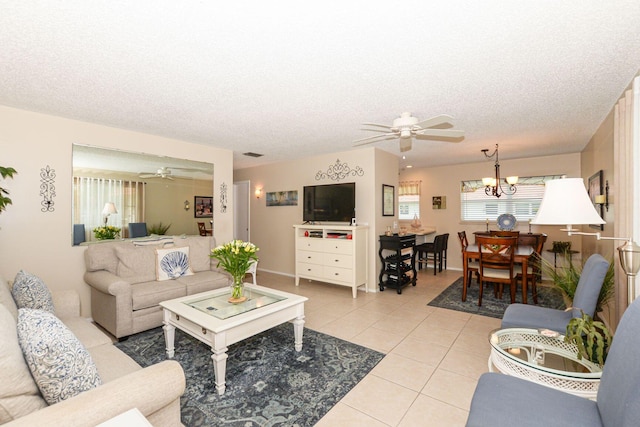 living room featuring ceiling fan with notable chandelier, a textured ceiling, and light tile patterned flooring