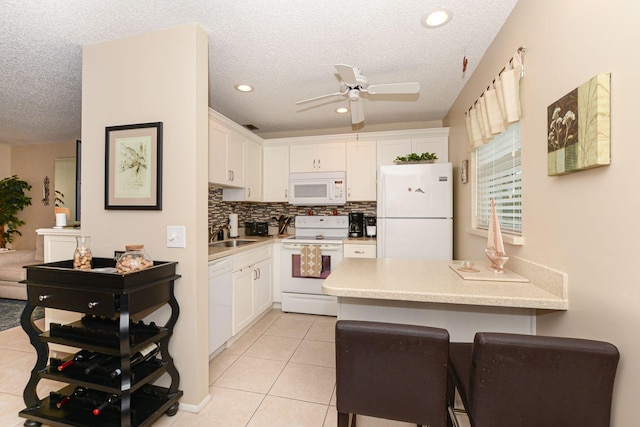 kitchen with white cabinetry, white appliances, a textured ceiling, and light tile patterned floors