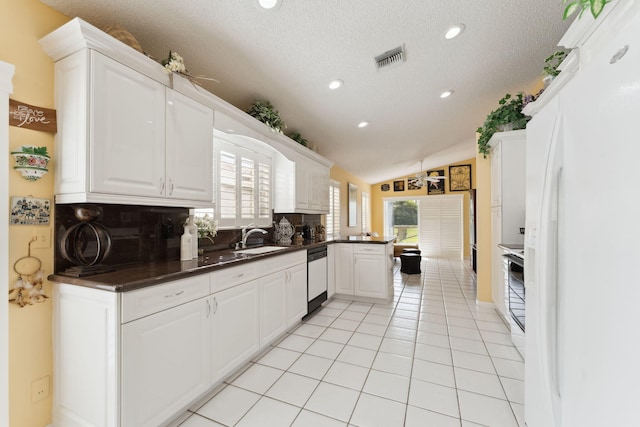 kitchen featuring white cabinetry, backsplash, white appliances, a textured ceiling, and vaulted ceiling