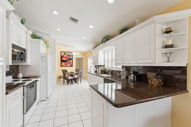 kitchen with kitchen peninsula, white appliances, vaulted ceiling, ceiling fan, and white cabinetry