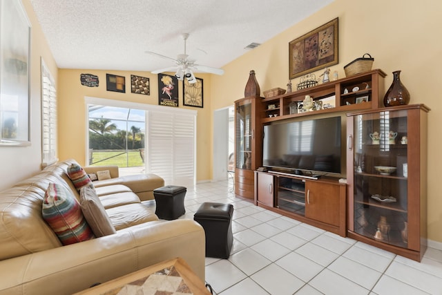 living room with ceiling fan, light tile patterned flooring, a textured ceiling, and vaulted ceiling