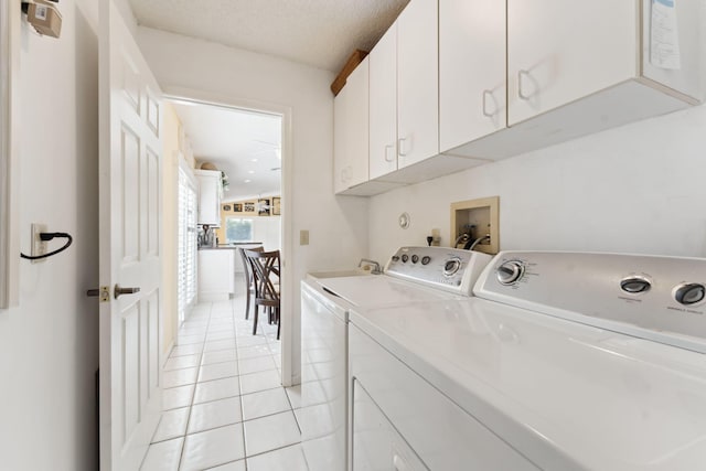 laundry room with cabinets, a textured ceiling, separate washer and dryer, and light tile patterned flooring