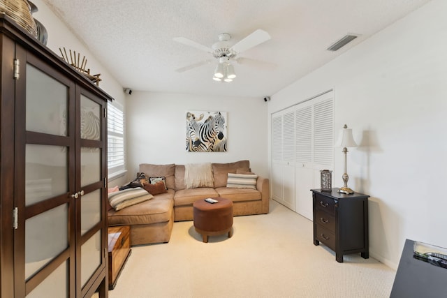 carpeted living room featuring ceiling fan and a textured ceiling