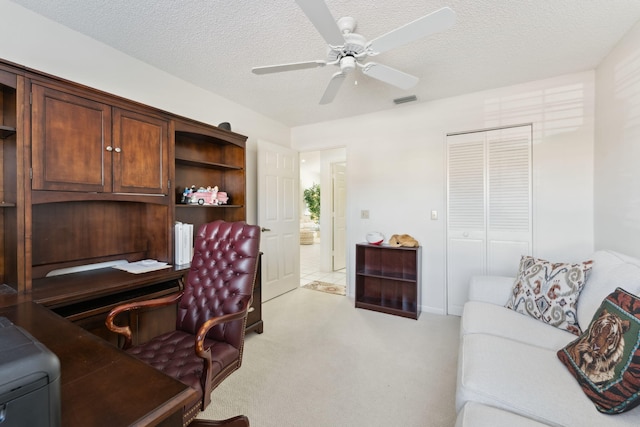 carpeted home office featuring ceiling fan and a textured ceiling