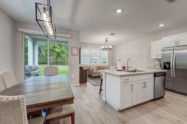 kitchen with white cabinetry, pendant lighting, appliances with stainless steel finishes, and an island with sink