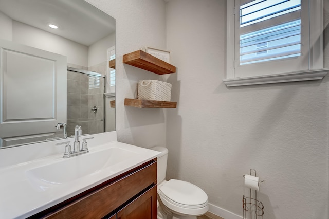 bathroom with toilet, vanity, and a shower with door