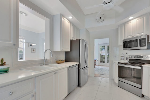 kitchen with sink, light tile patterned flooring, ceiling fan, stainless steel appliances, and white cabinets