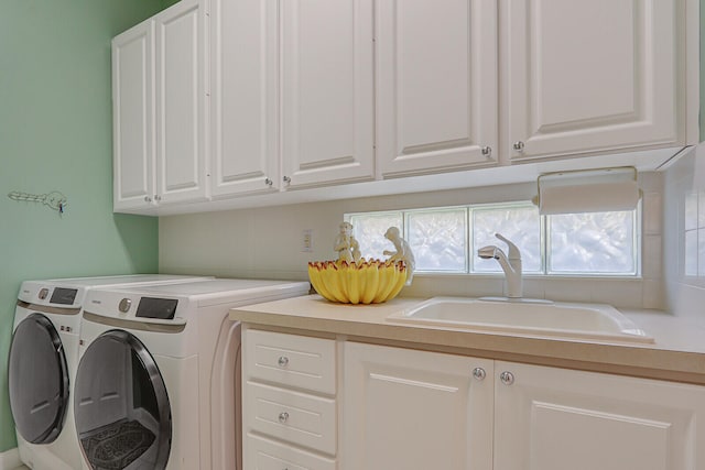 washroom with sink, washing machine and dryer, and cabinets