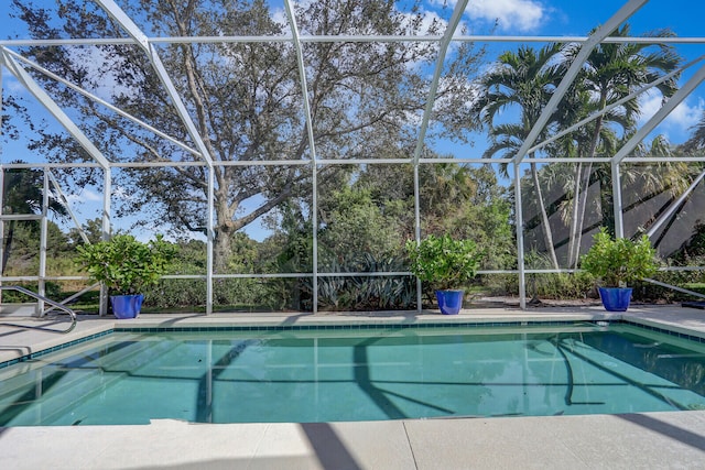 view of pool with a patio area and glass enclosure