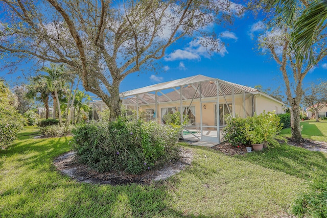 rear view of property featuring a patio area, a yard, and glass enclosure