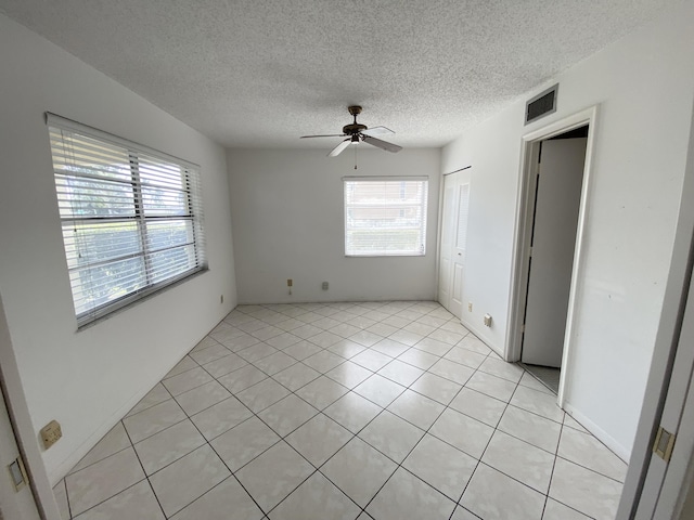 tiled spare room with ceiling fan and a textured ceiling