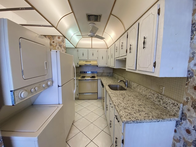 kitchen featuring white appliances, extractor fan, sink, stacked washer / dryer, and white cabinetry