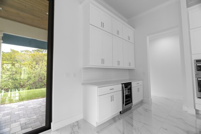 kitchen featuring stainless steel oven, crown molding, beverage cooler, white cabinetry, and tasteful backsplash