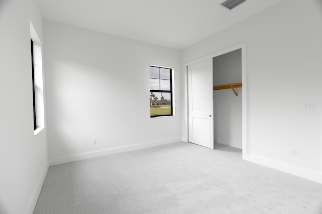 unfurnished bedroom featuring light carpet and a closet